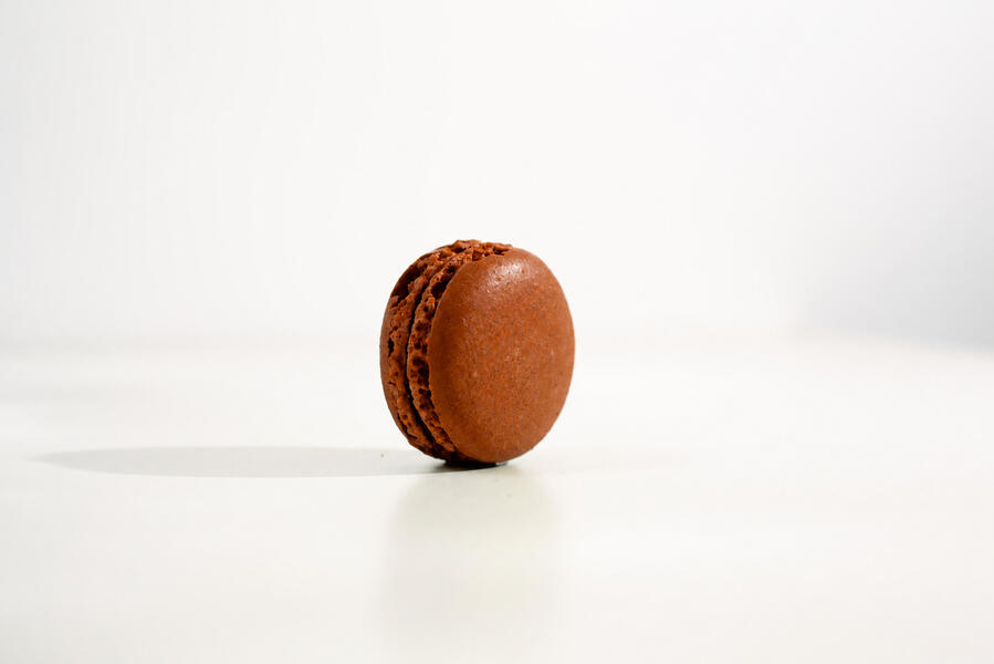 Kenyan black tea and São Tomé chocolate macaron, dark shell, on linen